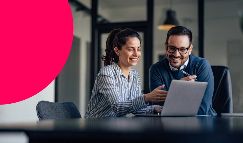 Two people in an office looking at a laptop screen
