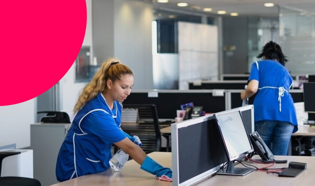 Two people cleaning desks in an office